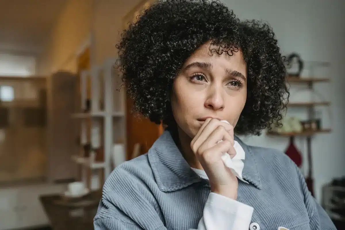 Frau sitzt nachdenklich da, innere Unruhe und emotionale Belastung sind sichtbar.