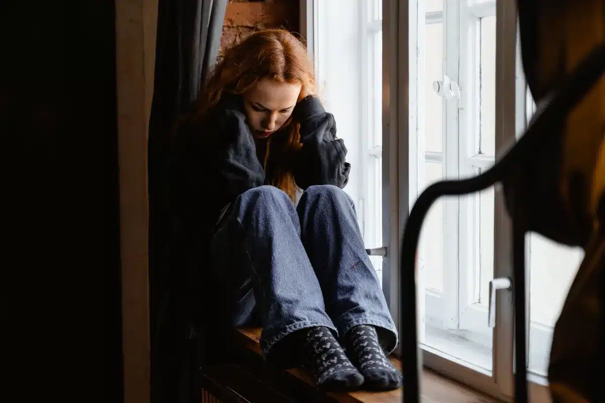 Frau sitzt nachdenklich und emotional belastet, symbolisiert die Schock- und Leugnungsphase nach einer Trennung