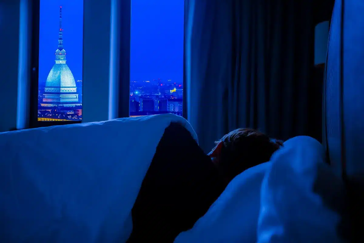 Person wälzt sich nachts im Bett, kann wegen Hitze nicht schlafen