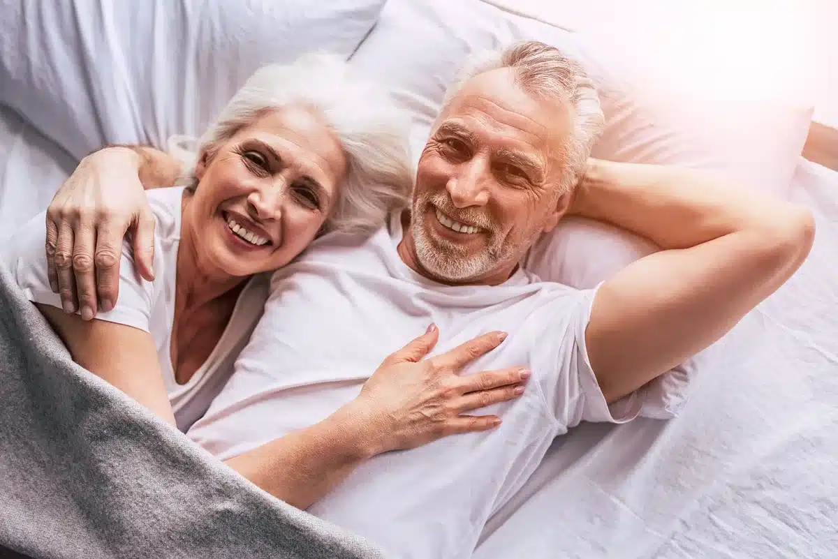 Zwei Personen sitzen im Abstand auf einem Sofa, sichtbar emotionale Distanz