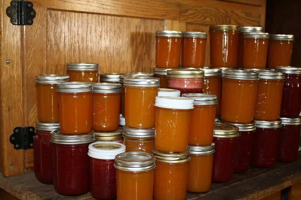 Glazen potten met zelfgemaakte jam en verse peren op een keukenblad