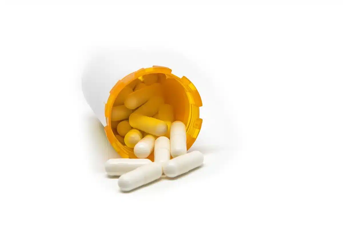 Verschreibungspflichtige Schmerztabletten neben einem Glas Wasser auf einem Nachttisch